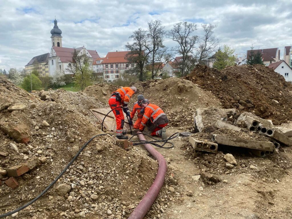 Arbeiter graben Kabel zwischen Erdhügeln.
