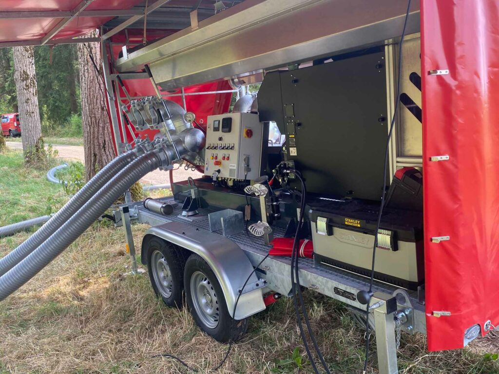 Technikanhänger mit Schläuchen, Waldumgebung.