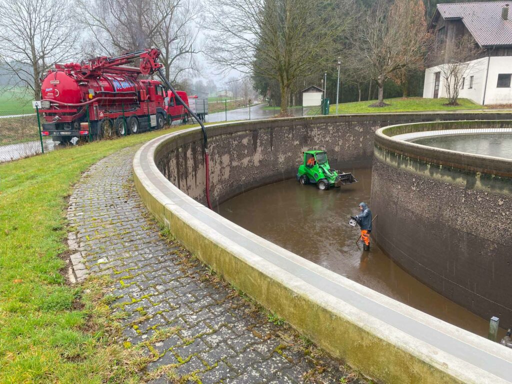 Grüner Radlader, Arbeiter, Klärbecken, Saugwagen.