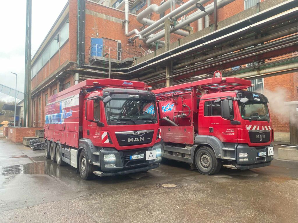 Zwei rote Lastwagen, Fabrikhintergrund.