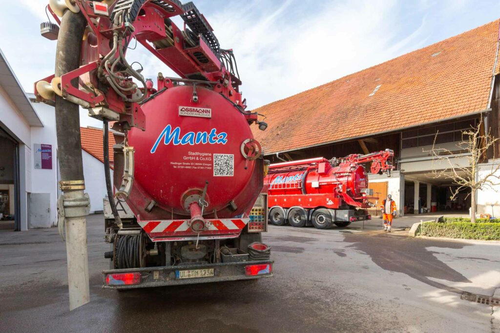 Rote Tankfahrzeuge vor Bauernhofgebäude.