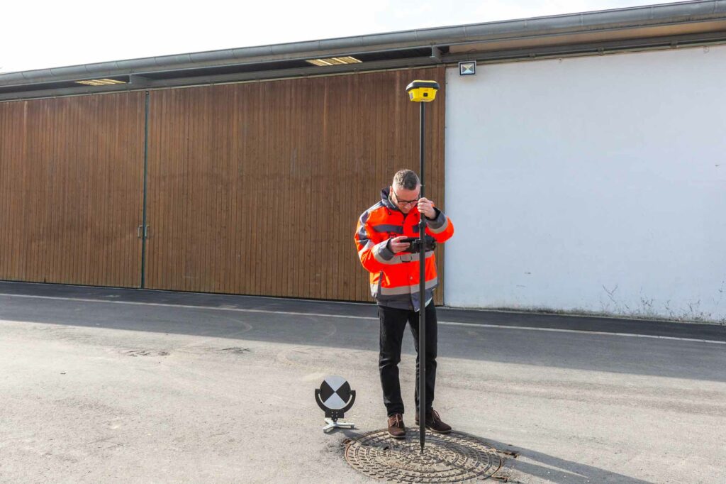 Vermessungsarbeit auf Kanaldeckel, Konzentration.