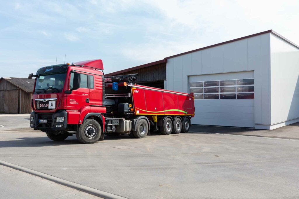 Roter LKW vor moderner Halle.