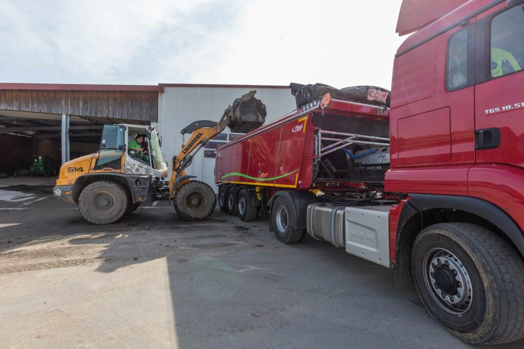 Radlader belädt roten Sattelauflieger.