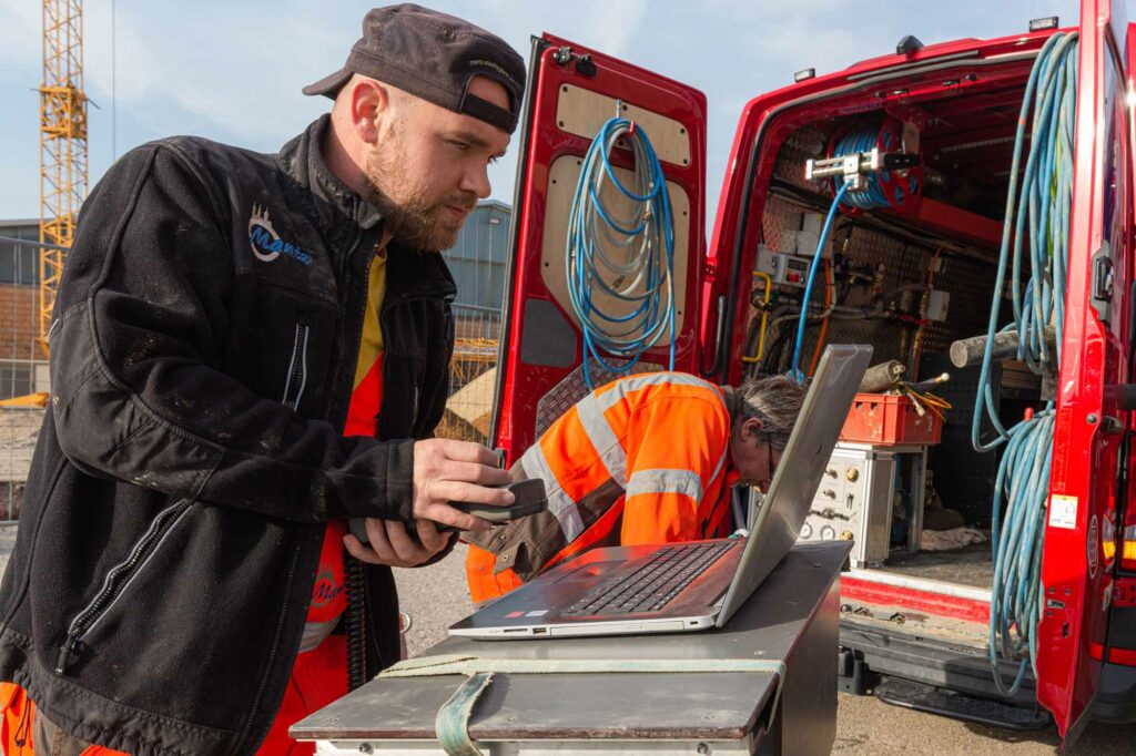 Techniker arbeiten draußen am Laptop.
