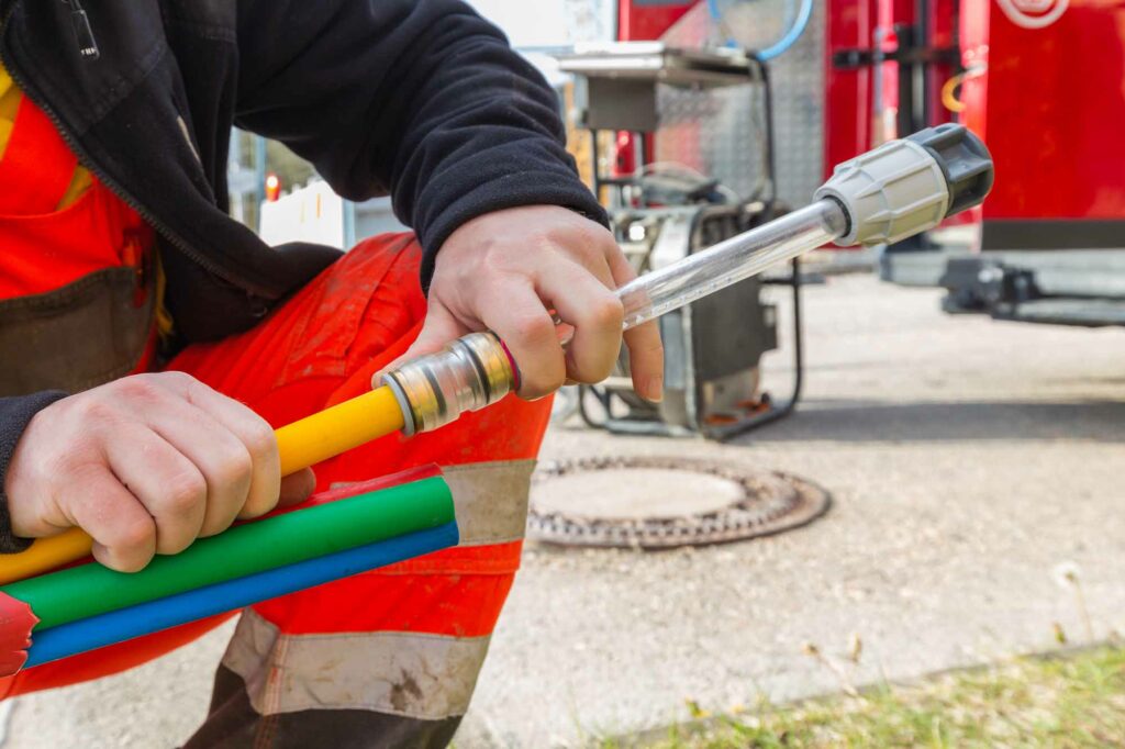 Hand hält bunte Kabelrohre fest.