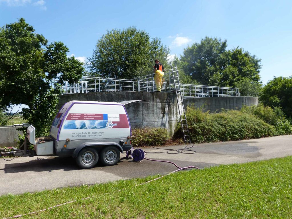 Arbeiter reinigt großen Betonbehälter.